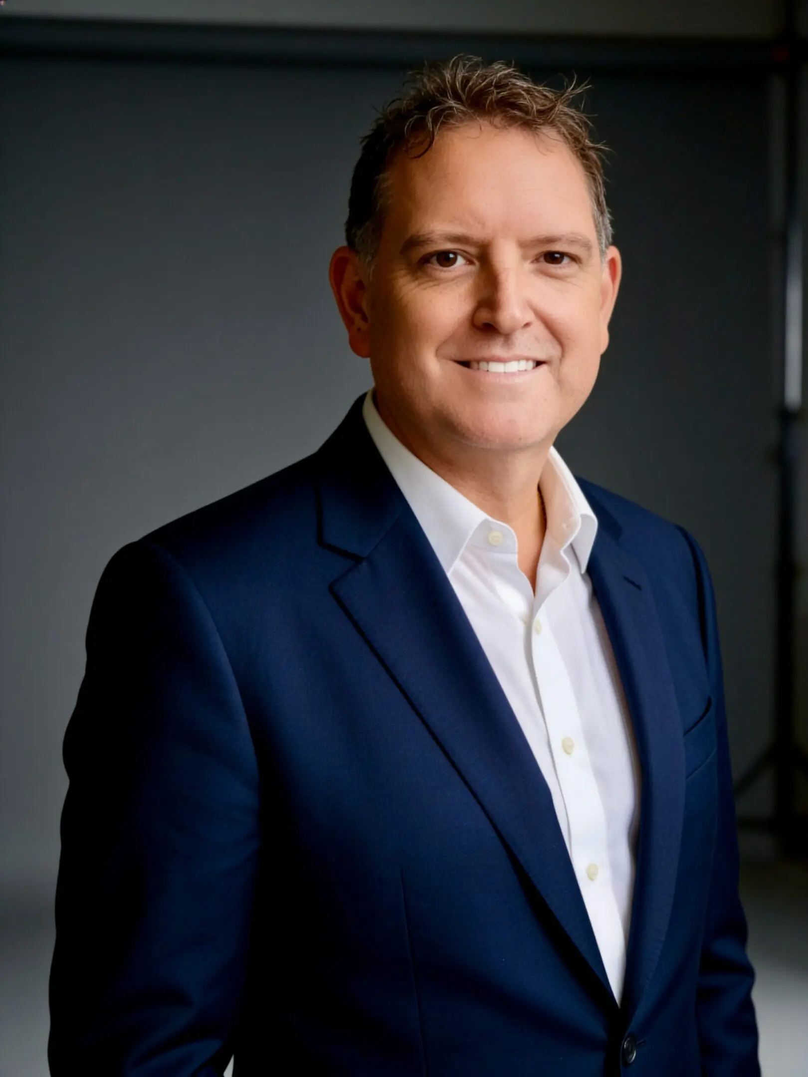 Professional headshot of smiling man in navy suit