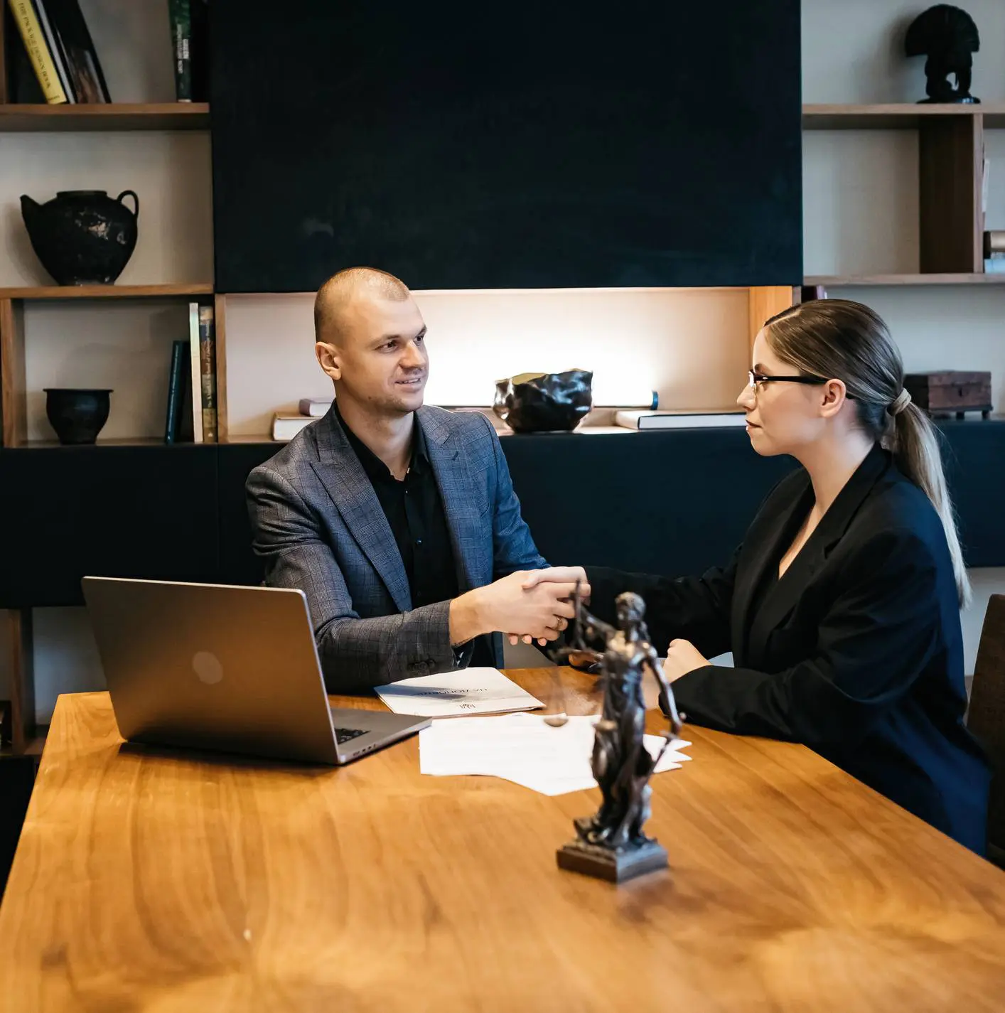 Business handshake between professionals at wooden desk